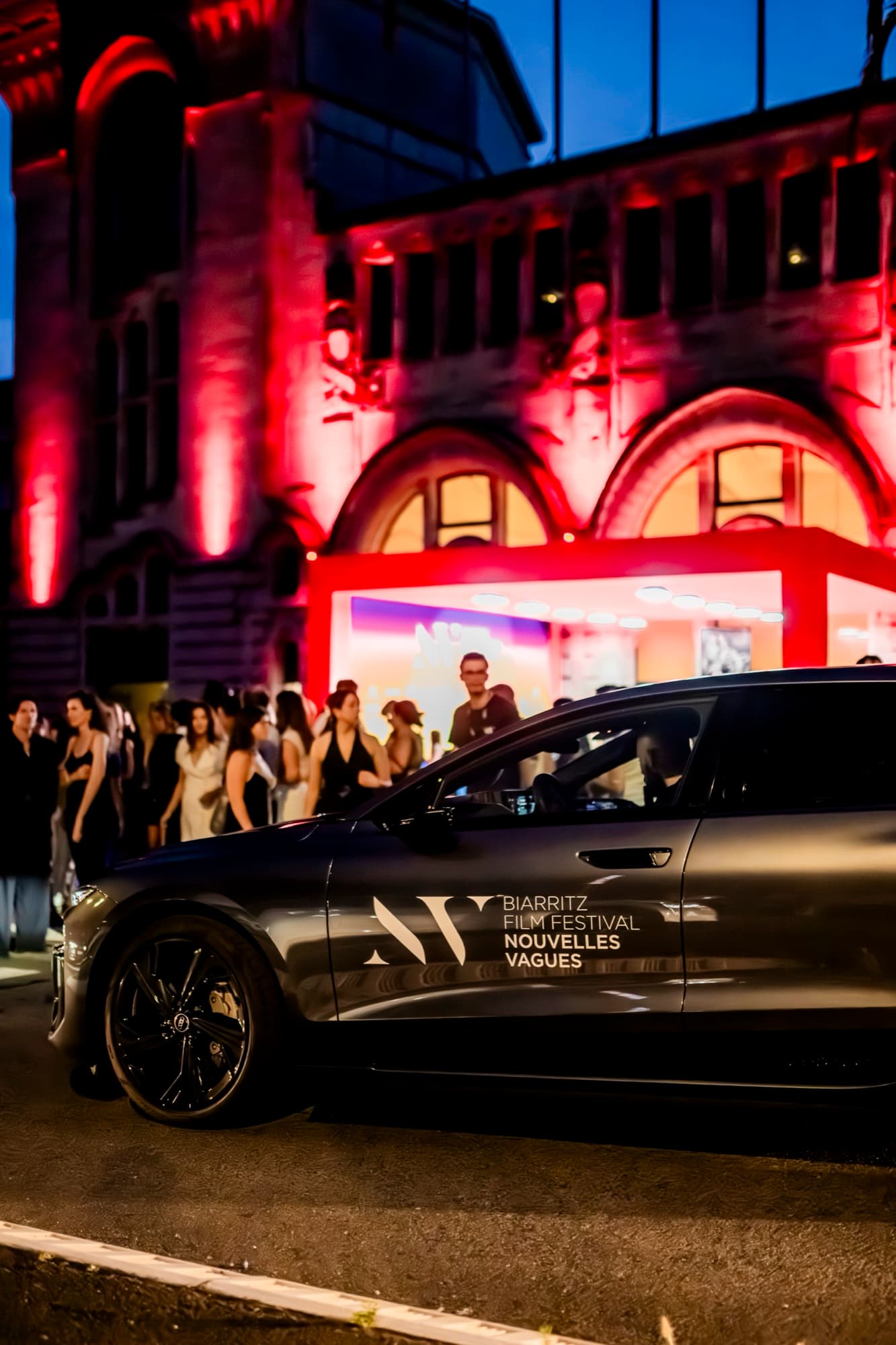 Dépose d'invités par un véhicule du festival Nouvelles Vagues à la nuit tombée